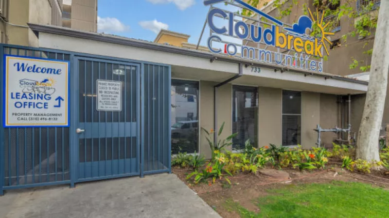 Cloudbreak Communities leasing office entrance with a blue gate, welcome sign, and landscaped garden.