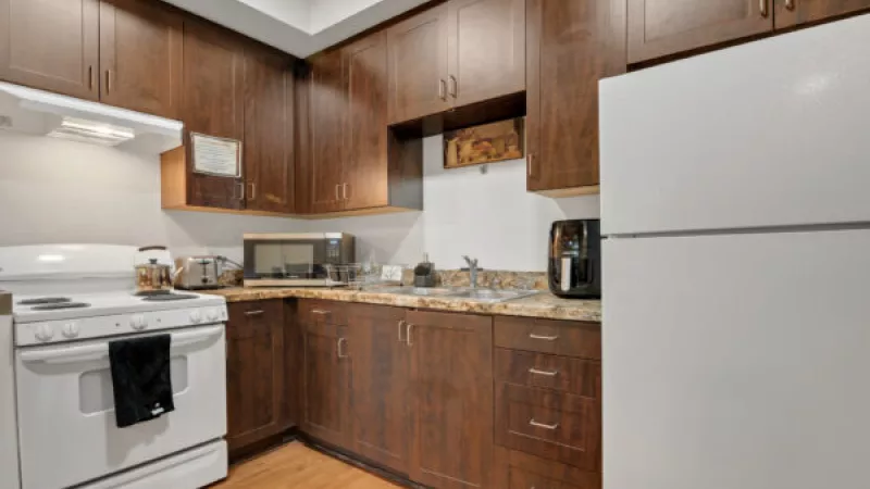 Small kitchen with dark wood cabinets, light countertops, white stove, and refrigerator.