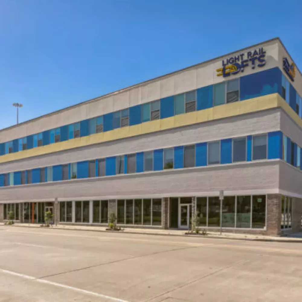 Modern three-story building with grey facade, blue and yellow window panels, and a Heartland Hospitality sign.
